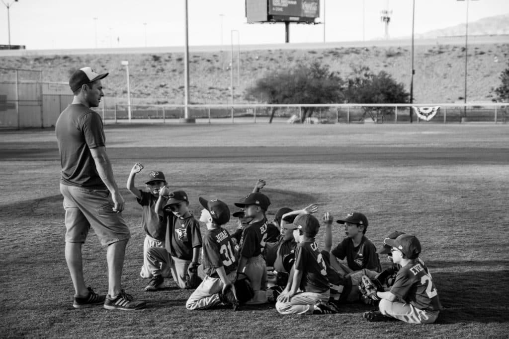 When summer hits, naturally parents want to avoid the summer slide. We want to schedule enough summer activities so that our children are challenged and go back to school ready. While all of this is done with the best of intentions, free play is more beneficial than most of these extracurricular activities for kids. This is why. Photo of kids listening to baseball coach. Photo credit unsplash photography.