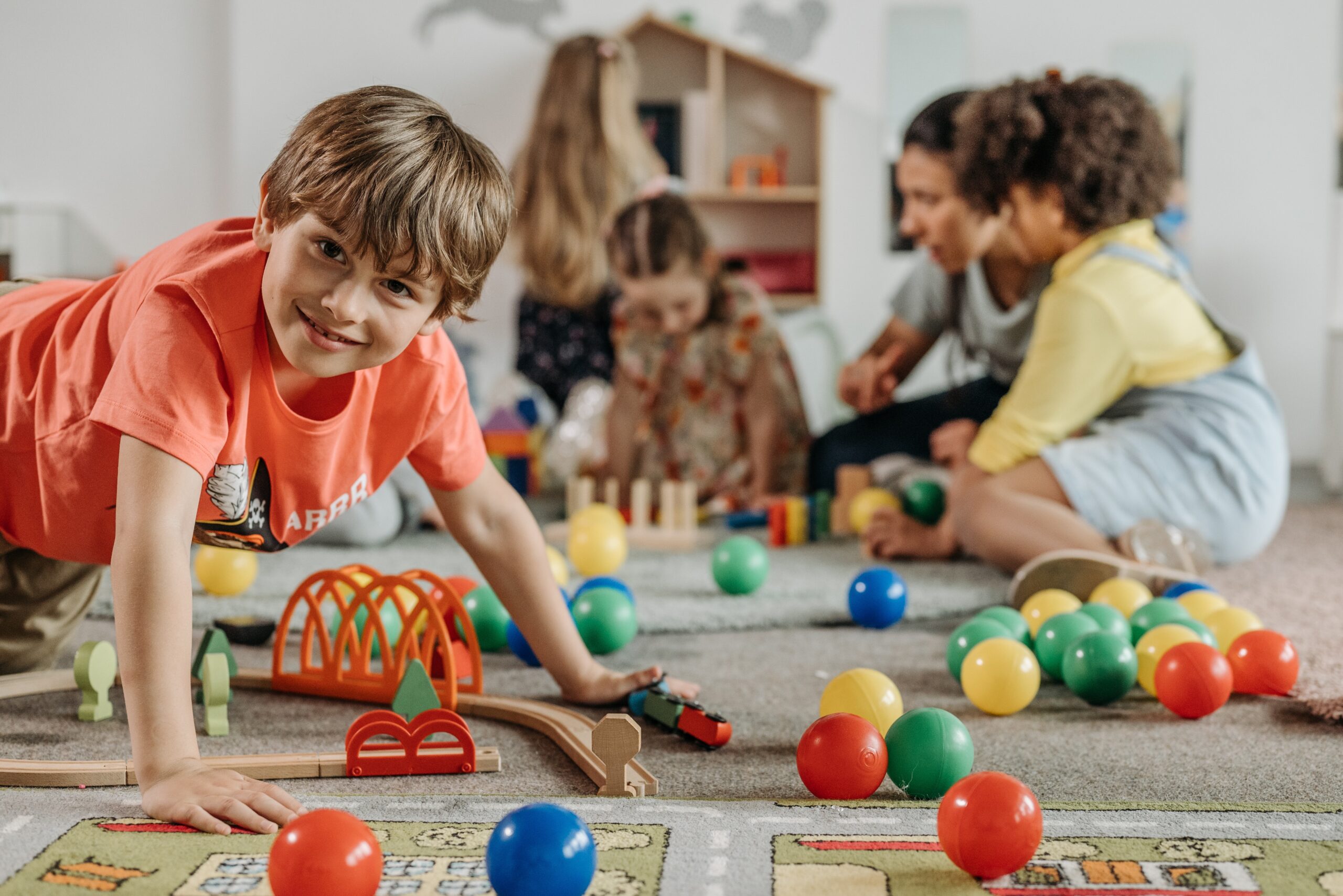 A young is happy playing with puzzles and balls, enjoying free play instead of structured activities.