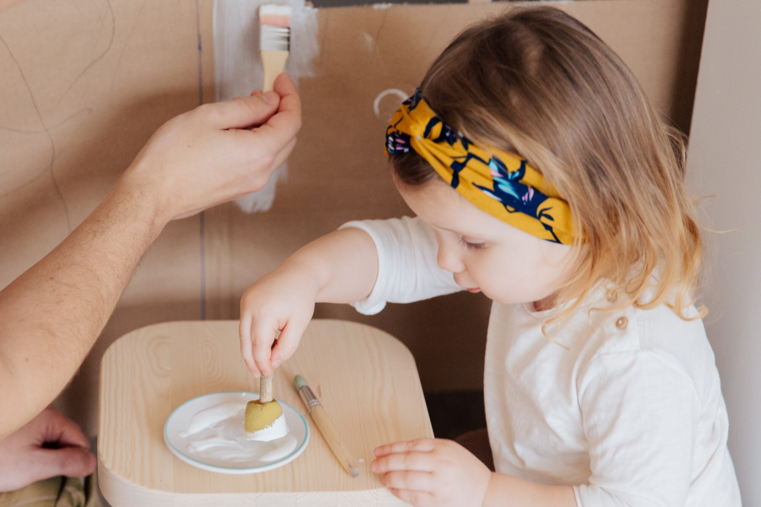 A toddler is having fun painting with a sponge.