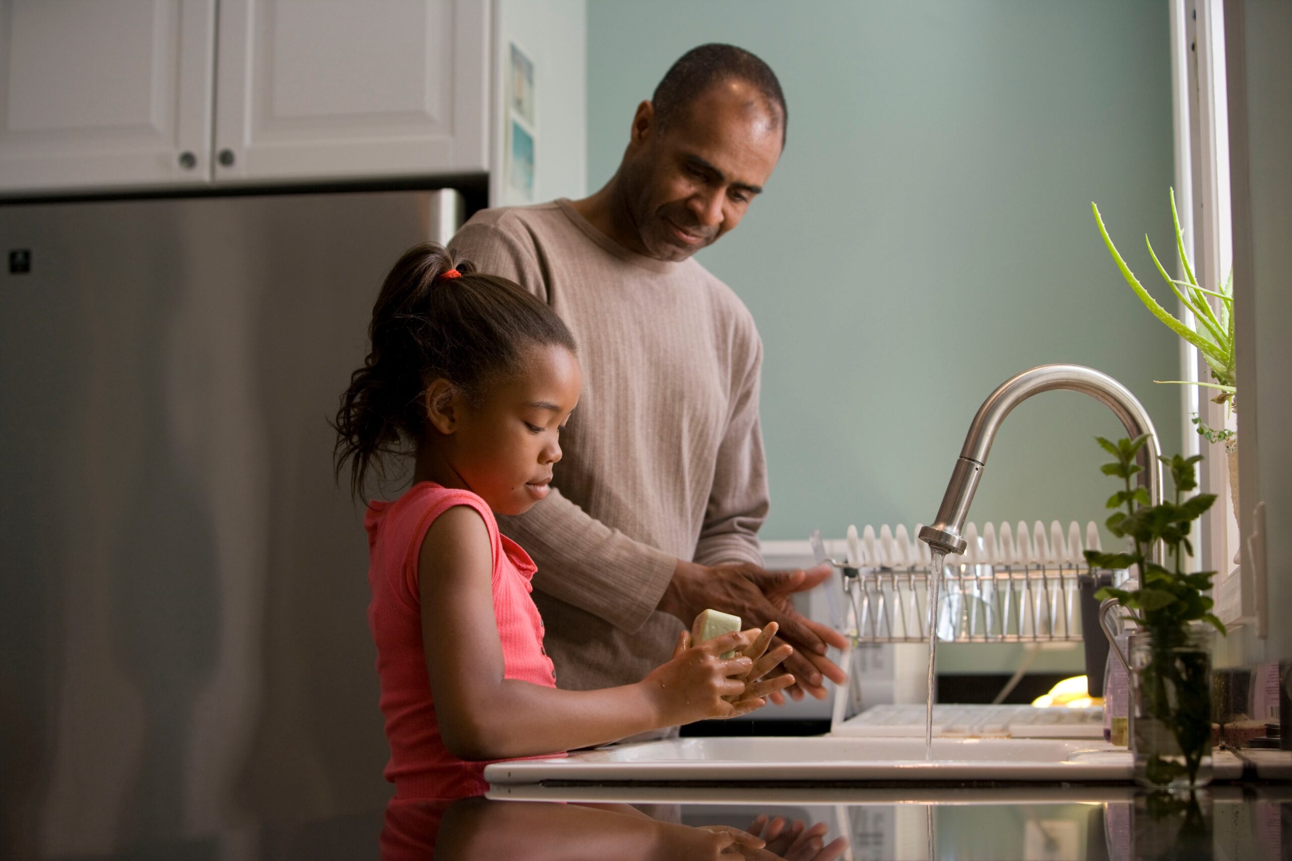 Father washing dishes with his daughter 