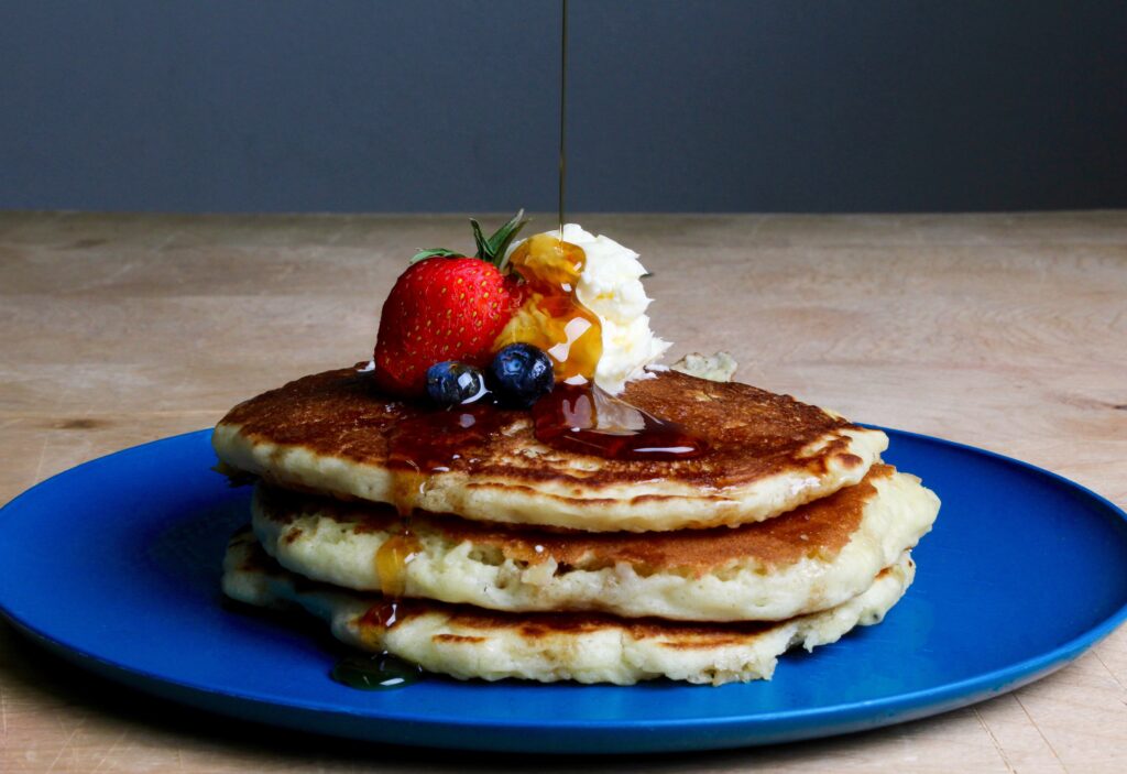 A blue plate with healthy pancakes topped with berries.