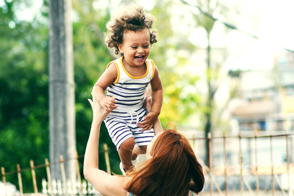 Happy baby laughing while mom throws him up in the air.
