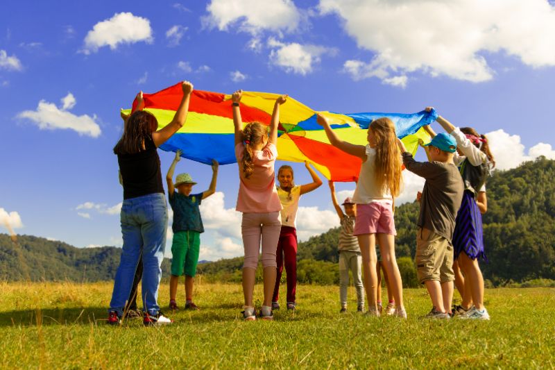 a circle of children playing together with a kite 