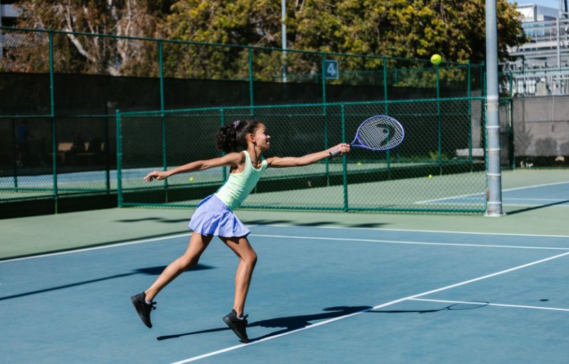 Girl playing tennis and working hard to master a new skill.