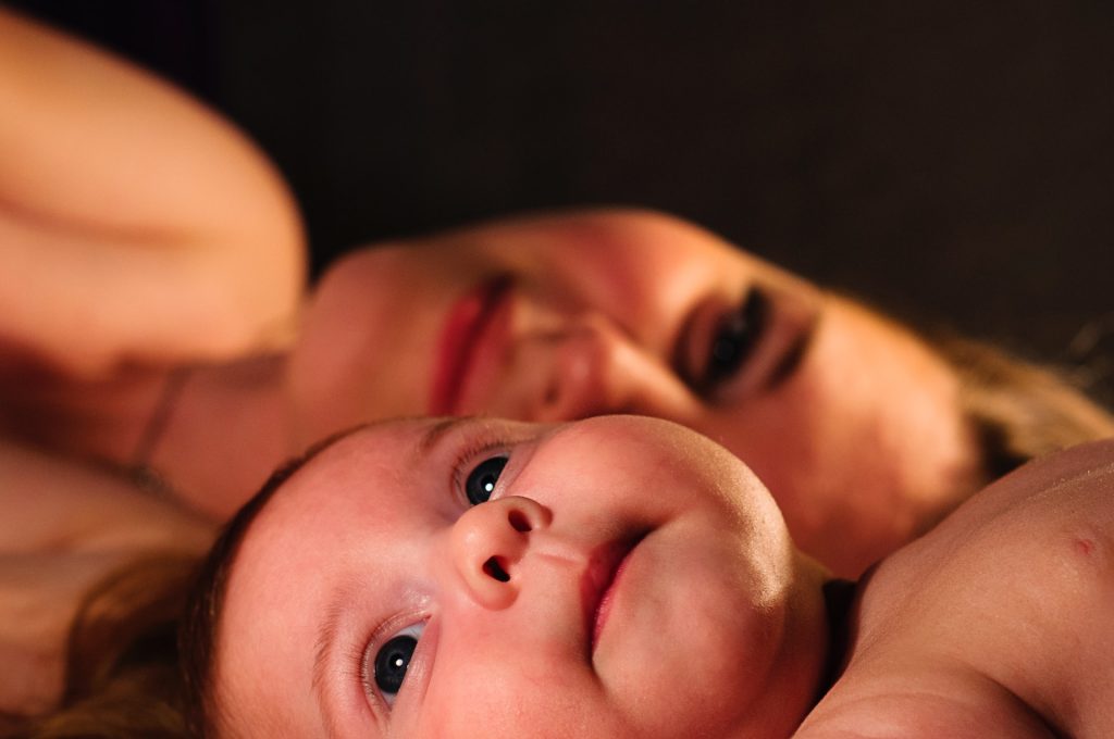 Mom smiles at the camera with baby in the forefront