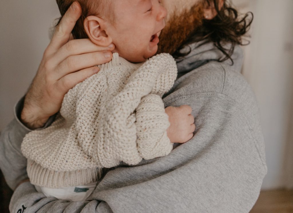 Dad holds crying baby in his arms during baby witching hour