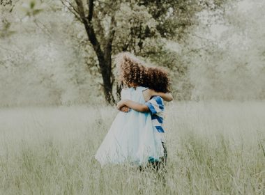 siblings hugging each other in a field of flowers.