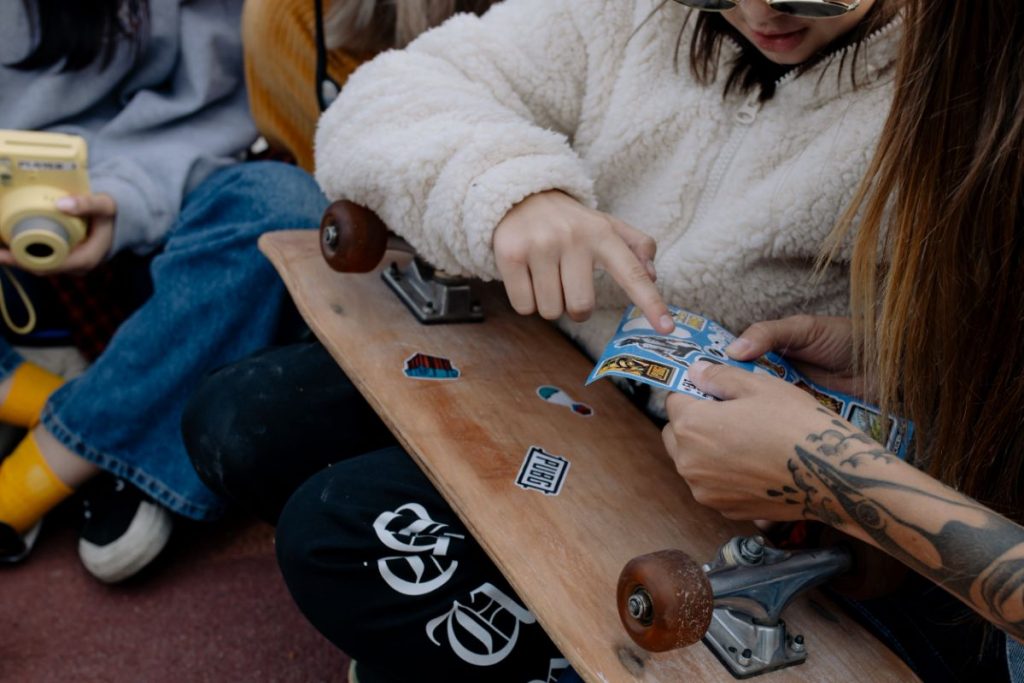 two children putting stickers on a skateboard