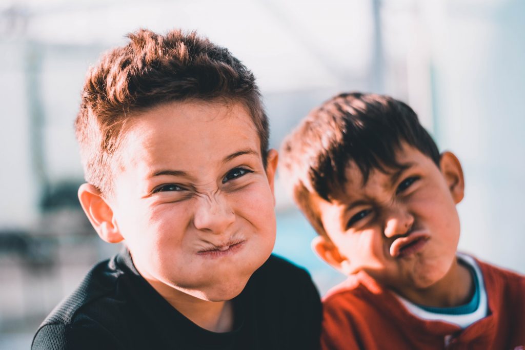 Two school-age boys make silly faces at the camera