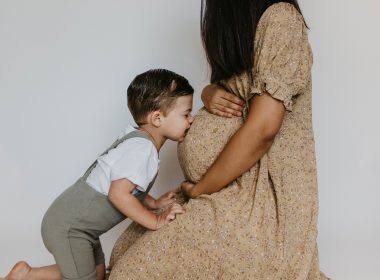 maternity photoshoot with pregnant mom and a boy kissing the belly.