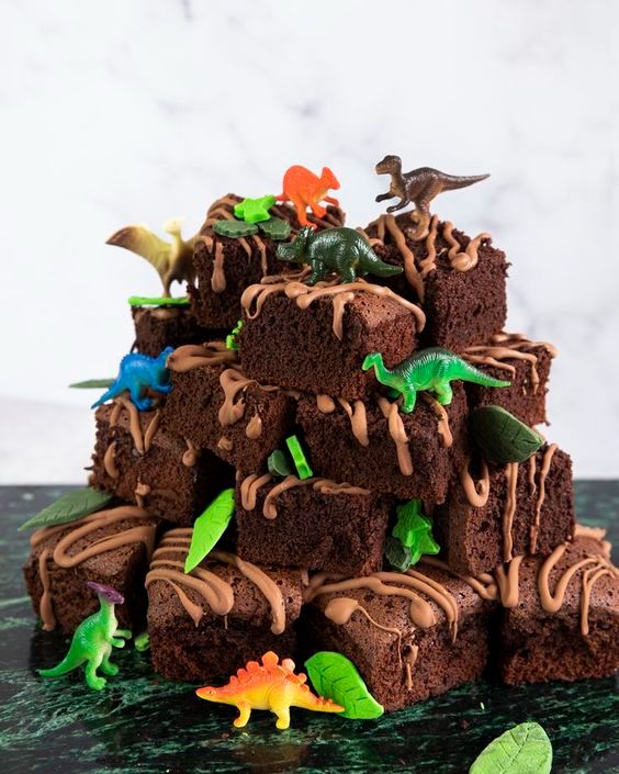 A stack of brownies with dinosaur decors.