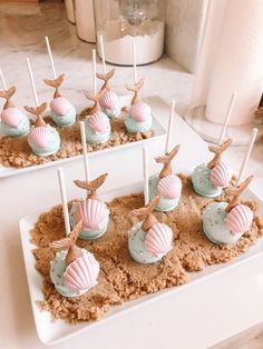Several cupcakes with mermaid tails, sticks, and shells as toppings.