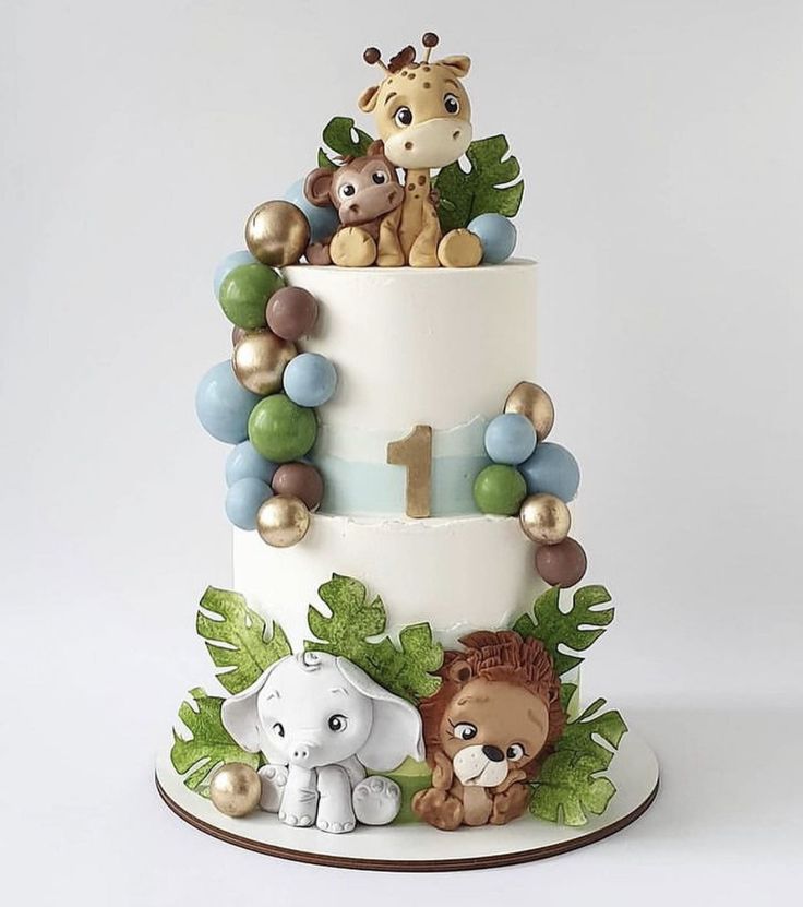 2-layer white safari cake adorned with jungle animals, baloons, and leaves.