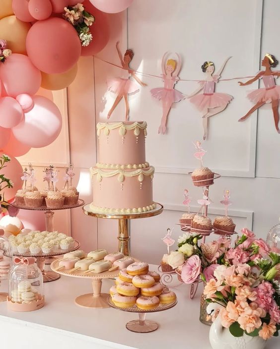 Ballerina-theme table set up, backdrop, pastries, and flowers in vases.