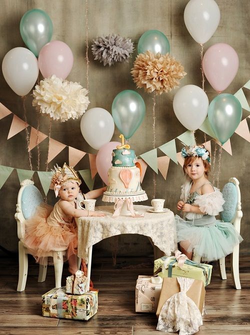 Two little girls celebrating the younger one's first birthday party with a princess tea party theme.