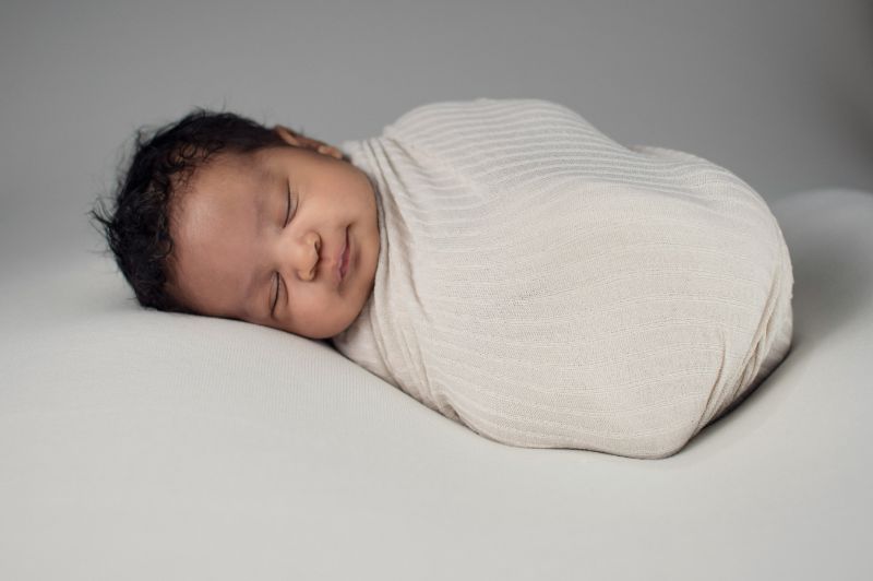 a baby swaddled with a white blanket
