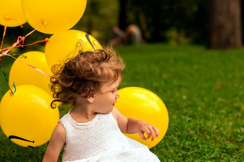 Little girl holding a lot of yellow balloons.