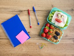 Appetizing school lunch and stationery on a table.