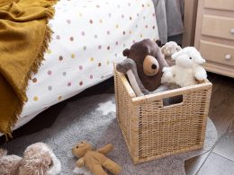 A rattan basket with stuffed animals on a bedroom floor.