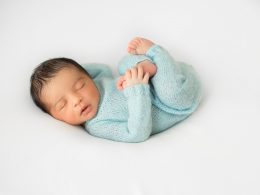 Sleeping newborn in blue overalls.