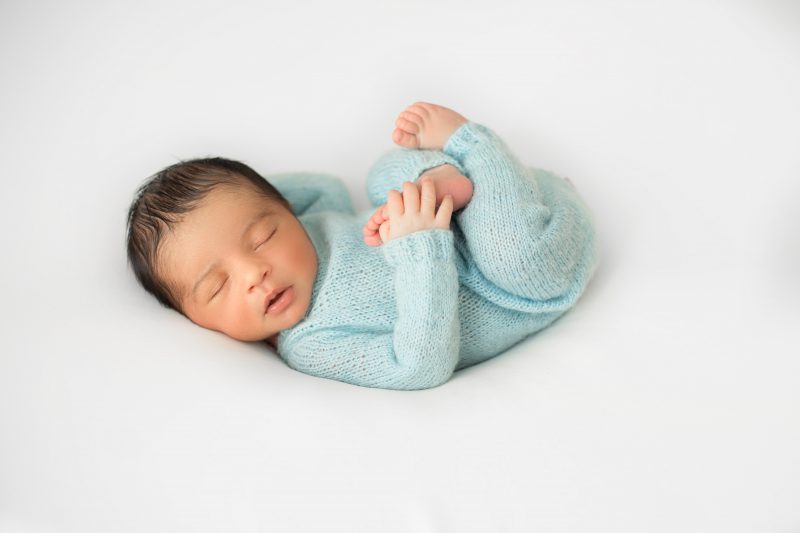 Sleeping newborn in blue overalls.