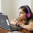 Girl on a computer with headphones on.