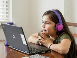 Girl on a computer with headphones on.