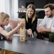 Mom and dad looking at their daughter as she plays jenga.