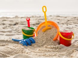 Three buckets with sand and a spade on tropical sand beach