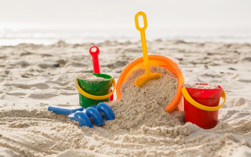 Three buckets with sand and a spade on tropical sand beach