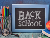 A small blackboard with the text "Back to School", magnifying glass, pencils, book, and apple.